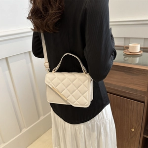 Sac bandoulière blanc matelassé avec détails dorés et poignée dans un décor chic