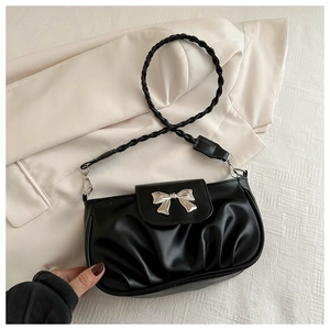 Détail du sac à bandoulière plissé noir avec un accessoire de nœud argenté proéminent