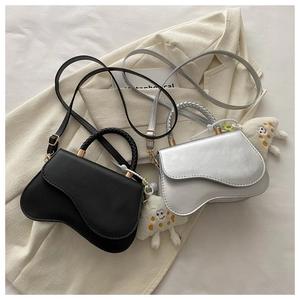 Close-up of wavy crossbody bags in black and silver with white cloud plush charms