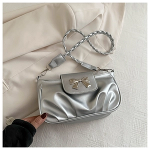 Détail d'un sac à bandoulière tressé argenté avec nœud métallique et texture plissée