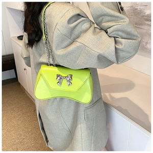 Detail of neon green crossbody bag featuring a silver bow buckle and glossy PU leather
