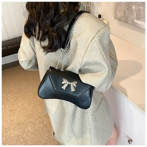 Close-up of a black crossbody bag with a silver bow buckle and chain shoulder strap