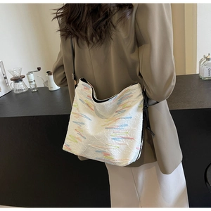 Détail d'un sac blanc avec broderie ondulée colorée et fine bandoulière en cuir noir