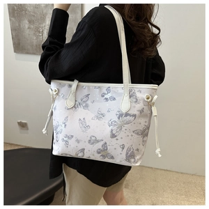 Détail du sac cabas blanc avec imprimés papillons violets et motifs étoilés