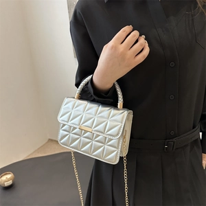 Silver quilted crossbody bag with metallic finish and gold chain strap on female model