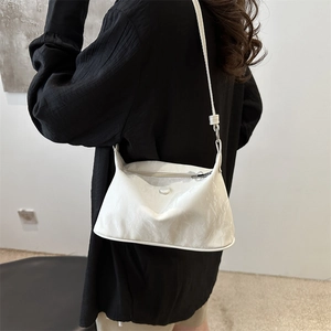 Sac fourre-tout blanc en cuir plissé avec fermeture éclair sur l'épaule du modèle