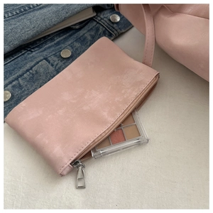 Close-up of a small pink makeup pouch with zipper and inner storage for eyeshadow palette