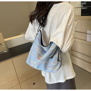 Détail du sac bandoulière bleu clair avec broderie de vagues et longue bandoulière noire