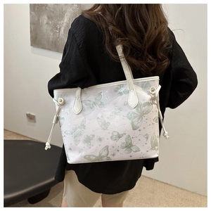 Détail d'un sac cabas blanc avec imprimé papillon vert porté à l'épaule pour femme