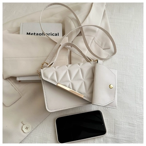 Detail of white quilted handbag set with golden metal bar and matching mini pouch