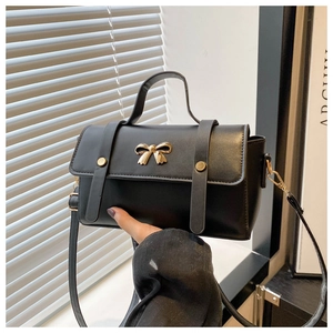 Detail of vintage matte leather crossbody bag featuring a gold bow buckle and top handle