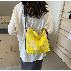 Détail du sac cabas jaune avec broderies ondulées colorées et bandoulière noire fine