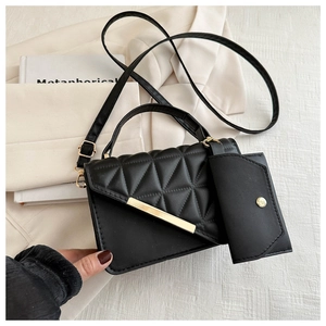 Detail of black quilted leather shoulder bag with gold hardware and removable mini pouch