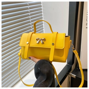 Detail of yellow PU leather bag with silver metal bow and adjustable strap