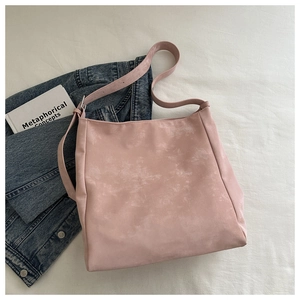 Close-up of pink faux suede tote bag with adjustable strap in a casual lifestyle setting
