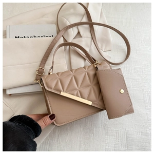 Close-up of beige quilted crossbody bag with golden metal trim on white blazer