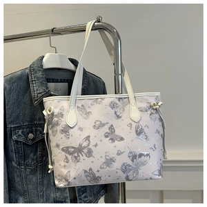 Détail du grand sac cabas blanc à motif papillon argenté sur un support en métal