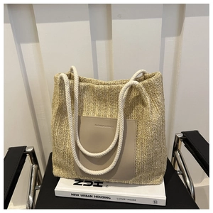 Close-up of woven straw tote bag with rope handles and a leather brand patch