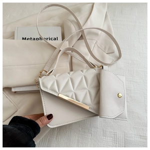 Detail of cream quilted crossbody bag with gold metal trim and matching coin purse charm