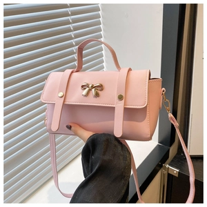 Detailed view of pink crossbody bag featuring gold bow hardware and PU leather flap