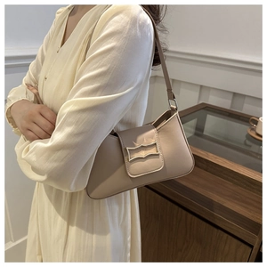 Beige baguette bag with gold buckle shown on shoulder for a stylish retro look