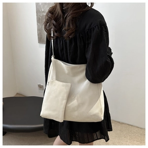 Detail view of large white faux leather tote bag with a matching small hanging pouch