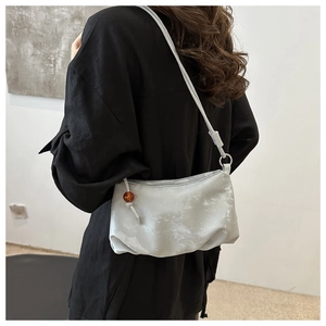 Détail du sac croissant gris clair texturé avec perle d'ambre et bandoulière en cuir