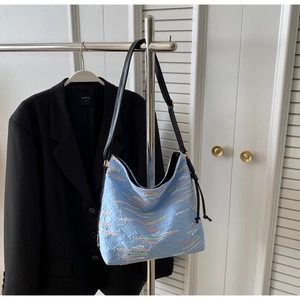 Détail d'un sac cabas bleu clair avec broderie vagues colorées et fine bandoulière noire