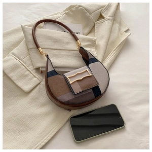 Detail of color-block hobo bag with patchwork design and golden buckle on beige blazer