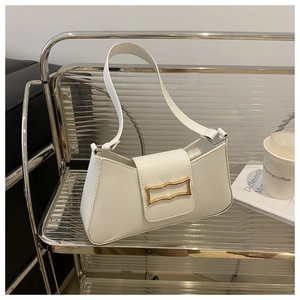 Close-up of white leather underarm bag featuring a golden rectangular buckle and magnetic flap