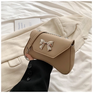Detail of khaki flap bag featuring a silver metal bow buckle and chain strap