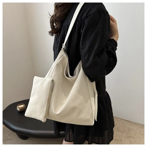 White minimalist tote bag set with matching pouch shown on shoulder in stylish room
