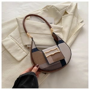 Detail of color-block saddle bag with brown leather handle and gold hardware buckle