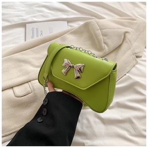 Detail of lime green crossbody bag with silver bow accent and elegant chain strap