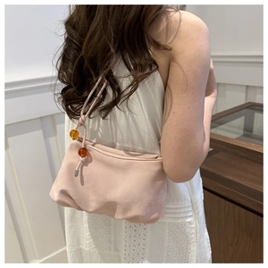 Détail du sac à bandoulière rose avec texture plissée et perles ambrées décoratives