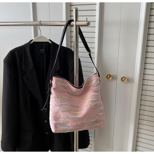 Détail du sac hobo rose brodé à motifs ondulés suspendu sur un cintre en inox