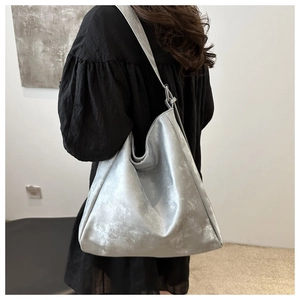 Detail of silver metallic hobo bag featuring soft textured faux leather and wide shoulder strap