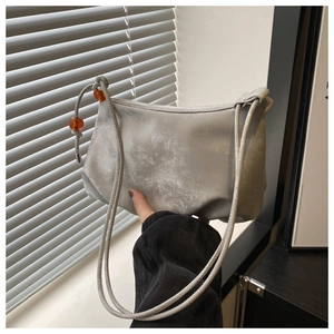 Détail du sac croissant argenté avec texture métallique et perles ambrées décoratives