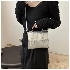Silver metallic textured square crossbody bag worn by a model in a black outfit