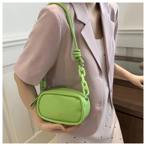Close-up of avocado green mini PU leather bag with decorative chunky chain on model