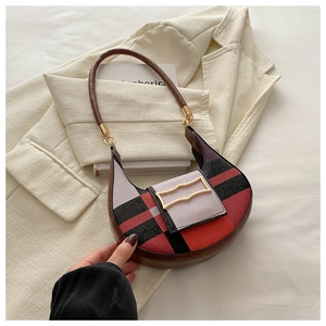 Detail of checkered hobo bag with vintage gold buckle on a chic blazer background