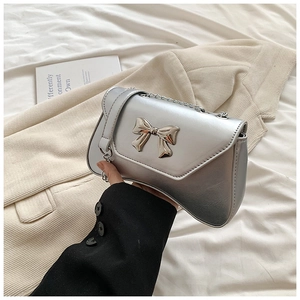 Detailed view of silver PU leather crossbody bag featuring a 3D metallic bow and chain