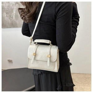Detail of white vintage crossbody bag with pleated texture and dual gold swivel buckles