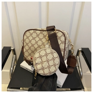 Detail of crossbody bag set with clover print, wide strap, and golden metal hardware