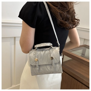 Detail of silver marble texture handbag with gold metal rings and crossbody strap