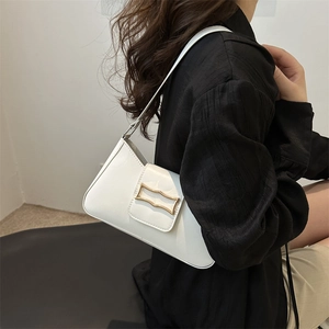 Minimalist white PU leather underarm bag with gold metal buckle shown on shoulder