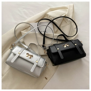 Detail of silver and black mini crossbody bags with golden bow buckles and fine leather texture