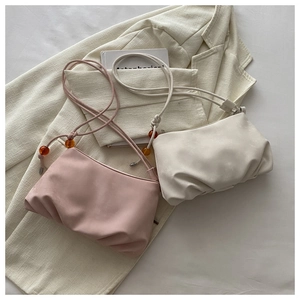 Détail de sacs nuages plissés en rose et beige avec des perles décoratives en ambre