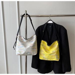 Détail de sacs demi-lune avec logos embossés et broderies de vagues arc-en-ciel