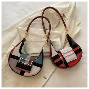 Detail of color-block geometric patchwork hobo bag with leather handle and gold buckle